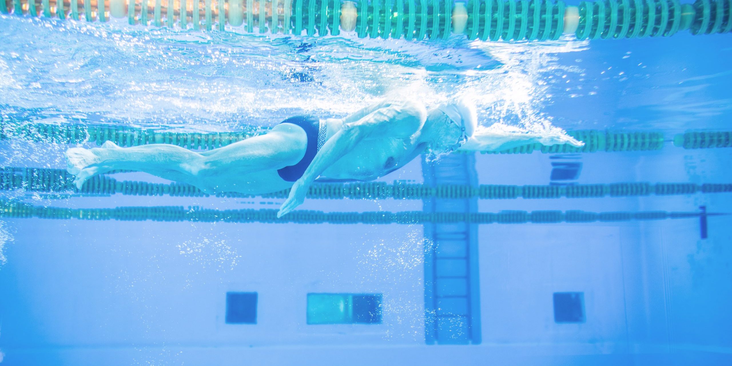 Senior man swimming in an indoor swimming pool.