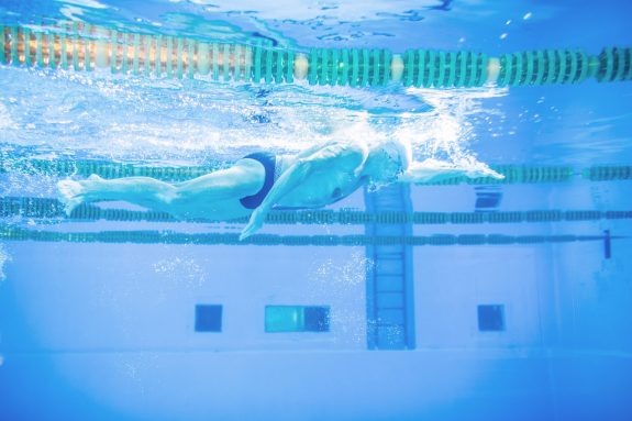 Senior man swimming in an indoor swimming pool.